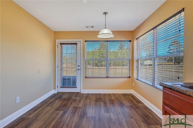 unfurnished dining area with dark hardwood / wood-style flooring and plenty of natural light