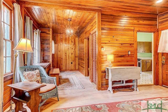 living area with light wood-type flooring, plenty of natural light, wood walls, and wooden ceiling