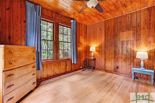 unfurnished room with ceiling fan, wooden ceiling, light hardwood / wood-style flooring, and wood walls