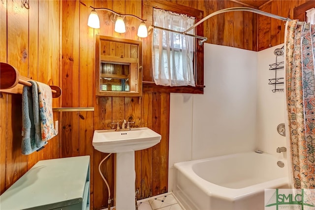 bathroom featuring sink, tile patterned floors, wood walls, and shower / tub combo with curtain