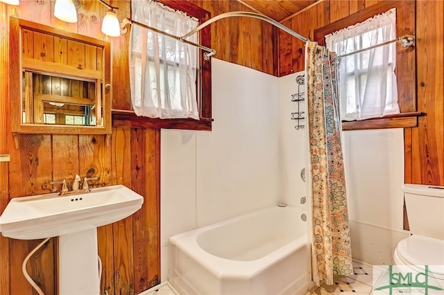 bathroom with toilet, shower / bathtub combination with curtain, tile patterned floors, and wood walls