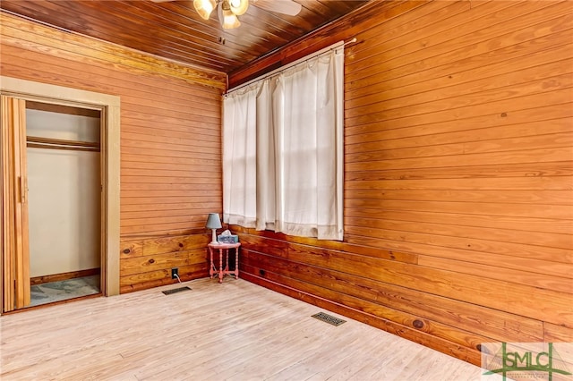 unfurnished bedroom with hardwood / wood-style floors, wood ceiling, a closet, wood walls, and ceiling fan