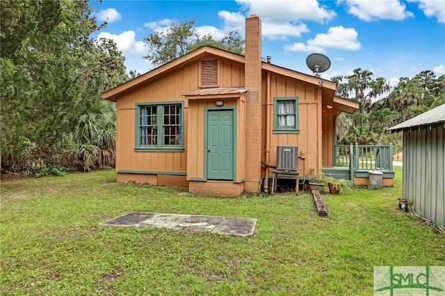 rear view of house with a lawn, central AC unit, and an outbuilding