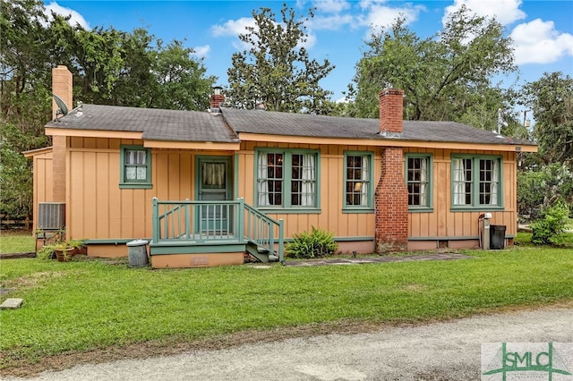 back of property with central air condition unit and a yard