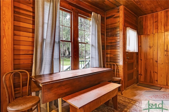 dining space with wooden ceiling, hardwood / wood-style floors, and wood walls