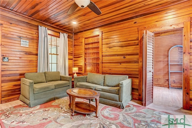 living room with ceiling fan, wooden ceiling, and wooden walls