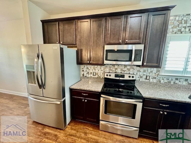 kitchen with tasteful backsplash, light stone countertops, stainless steel appliances, and dark brown cabinetry