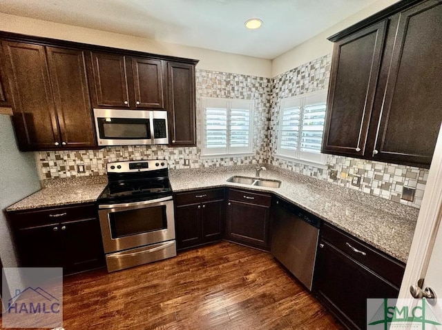 kitchen featuring decorative backsplash, sink, dark brown cabinetry, dark wood-type flooring, and appliances with stainless steel finishes