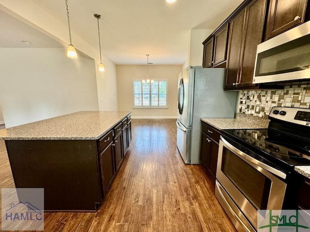 kitchen with decorative light fixtures, appliances with stainless steel finishes, an inviting chandelier, and a center island