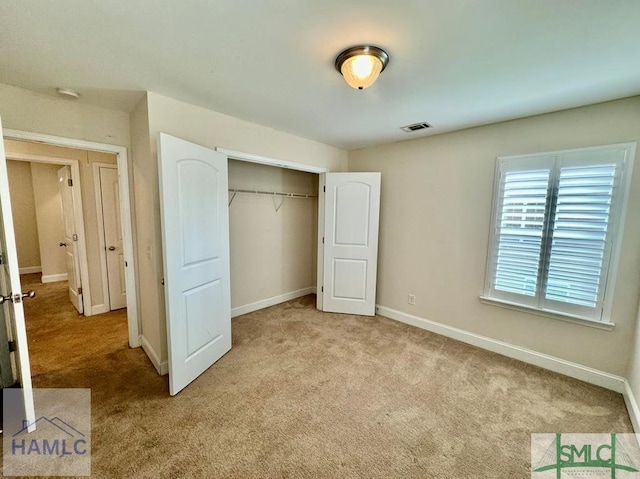 unfurnished bedroom with light carpet and a closet