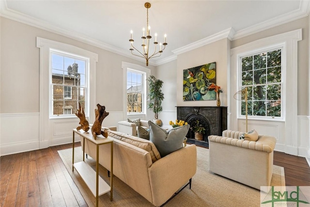 sitting room with hardwood / wood-style flooring, ornamental molding, and an inviting chandelier