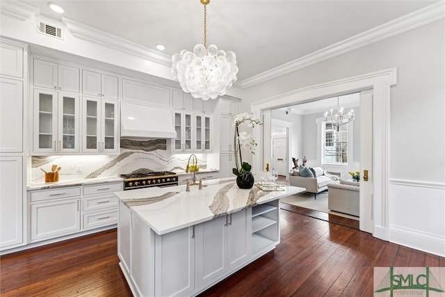 kitchen featuring pendant lighting, white cabinetry, an island with sink, and decorative backsplash