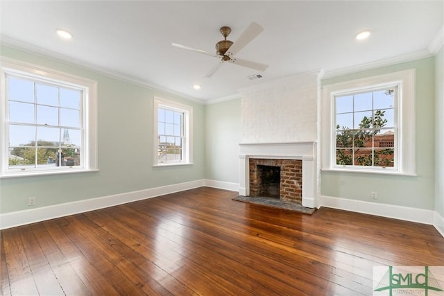 unfurnished living room featuring a brick fireplace, a healthy amount of sunlight, dark wood-type flooring, and ceiling fan