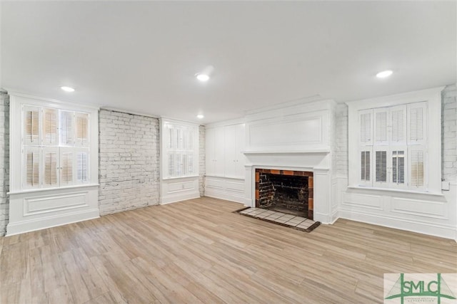 unfurnished living room featuring a large fireplace and light hardwood / wood-style floors