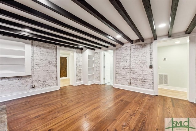 unfurnished living room featuring wood-type flooring and beamed ceiling