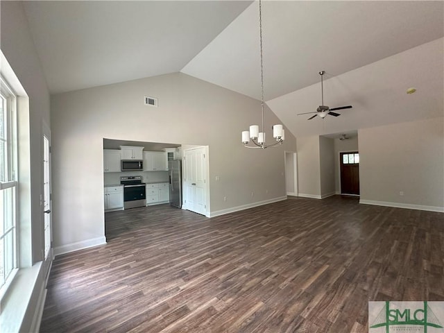 unfurnished living room with high vaulted ceiling, dark wood-type flooring, and ceiling fan with notable chandelier