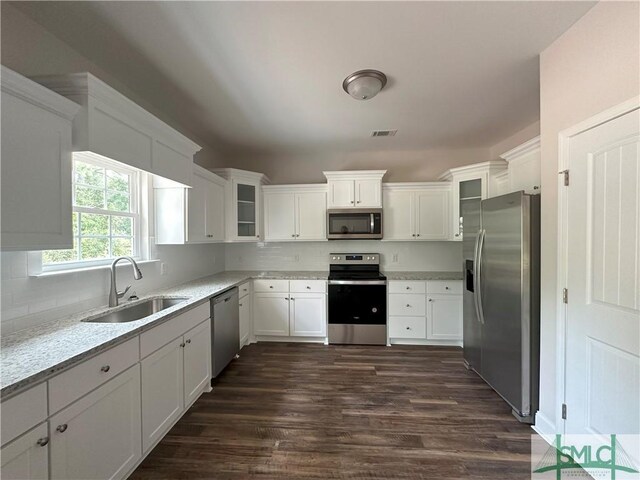 kitchen with dark wood-type flooring, white cabinetry, stainless steel appliances, sink, and light stone counters