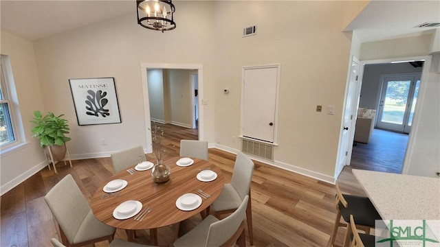 unfurnished dining area featuring a high ceiling, wood-type flooring, and an inviting chandelier