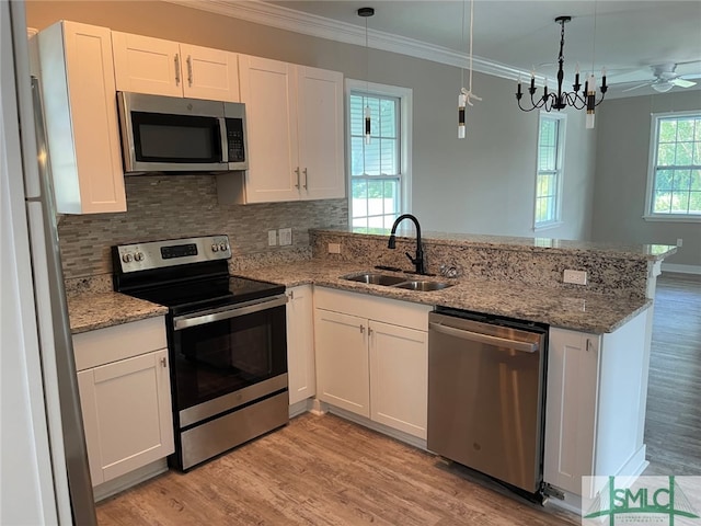 kitchen with pendant lighting, white cabinetry, stainless steel appliances, sink, and kitchen peninsula