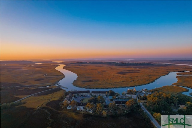 aerial view at dusk featuring a water view