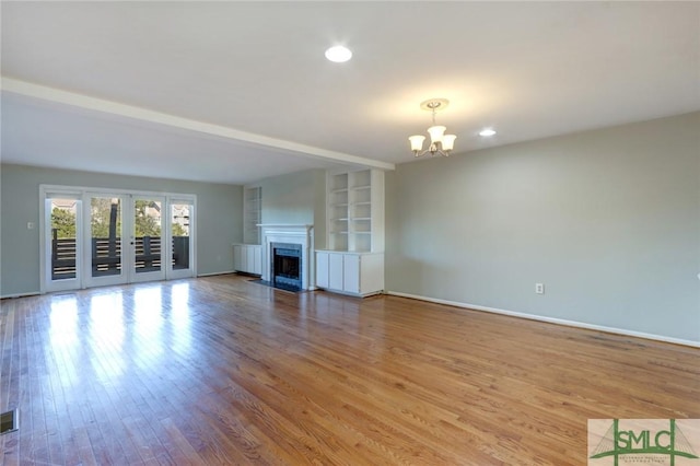 unfurnished living room with beam ceiling, hardwood / wood-style floors, and a notable chandelier