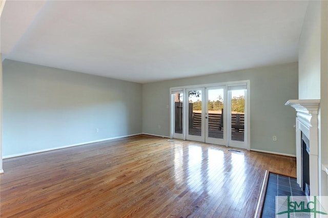 unfurnished living room featuring a tile fireplace and dark hardwood / wood-style flooring