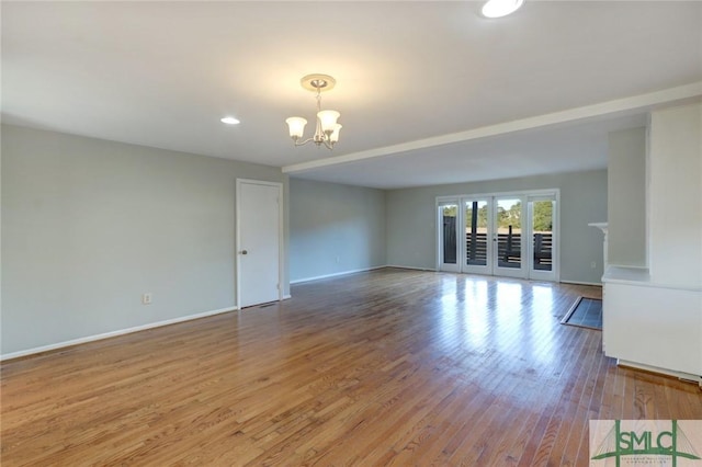 spare room featuring an inviting chandelier and light hardwood / wood-style flooring