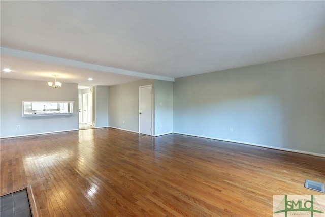 unfurnished living room with hardwood / wood-style flooring and a notable chandelier