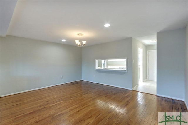 unfurnished room featuring hardwood / wood-style floors and an inviting chandelier