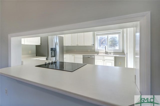 kitchen with kitchen peninsula, sink, stainless steel appliances, and white cabinetry