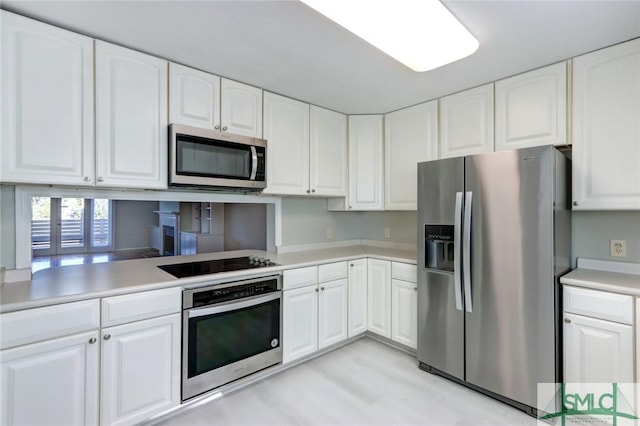 kitchen featuring kitchen peninsula, white cabinets, and stainless steel appliances