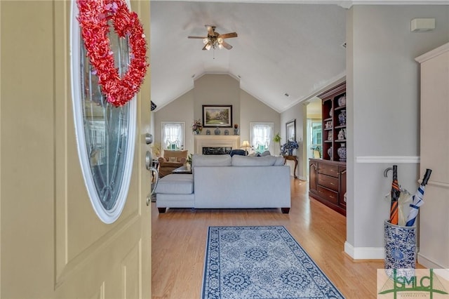 living room featuring ceiling fan, lofted ceiling, and light hardwood / wood-style flooring