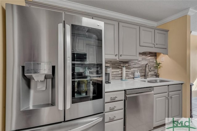 kitchen featuring appliances with stainless steel finishes, decorative backsplash, sink, gray cabinets, and crown molding