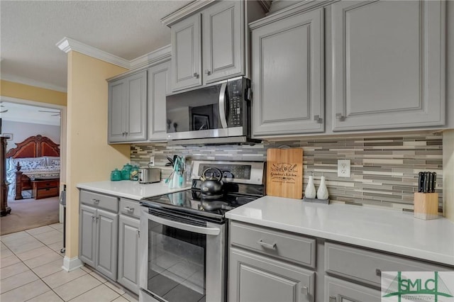 kitchen featuring light tile patterned floors, stainless steel appliances, decorative backsplash, and ornamental molding