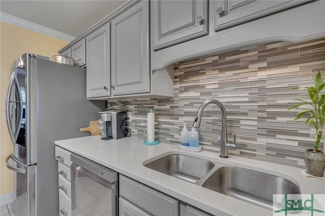 kitchen with stainless steel appliances, gray cabinetry, tasteful backsplash, crown molding, and sink