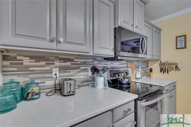 kitchen with gray cabinets, stainless steel appliances, decorative backsplash, a textured ceiling, and crown molding