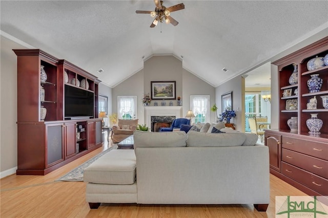 living room featuring light hardwood / wood-style floors, a textured ceiling, a high end fireplace, and vaulted ceiling