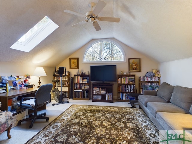 office with ceiling fan, vaulted ceiling with skylight, a textured ceiling, and carpet flooring