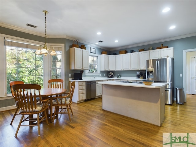 kitchen with white cabinets, appliances with stainless steel finishes, light hardwood / wood-style flooring, and pendant lighting