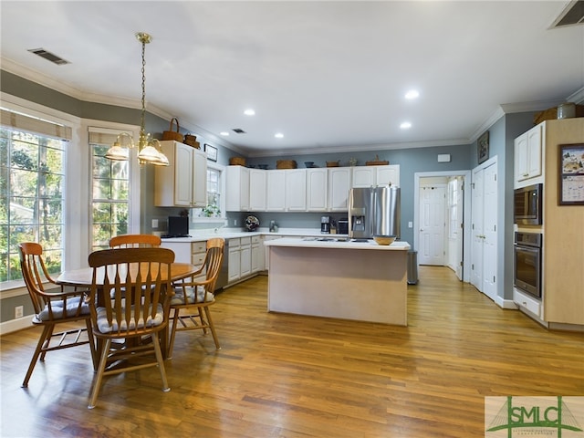 kitchen featuring decorative light fixtures, ornamental molding, stainless steel appliances, and a center island