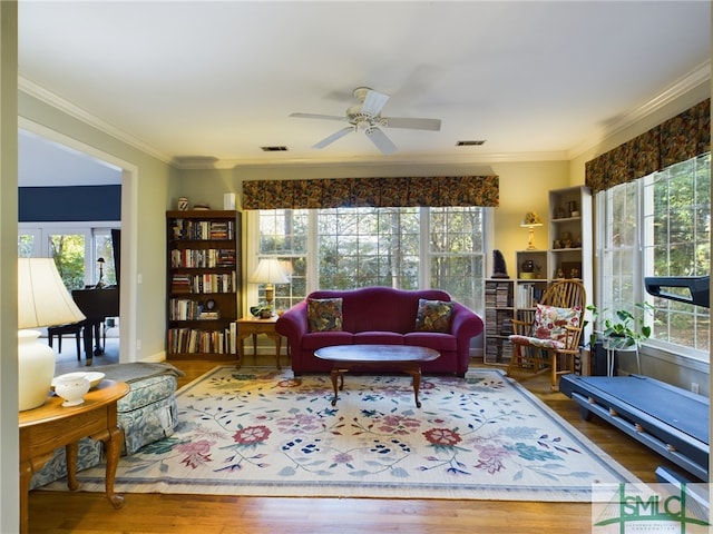 living room featuring ceiling fan, ornamental molding, and wood-type flooring