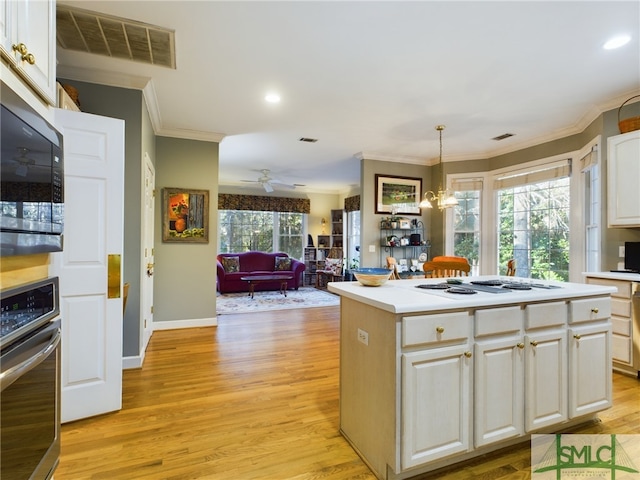 kitchen with stainless steel appliances, pendant lighting, white cabinetry, and a kitchen island