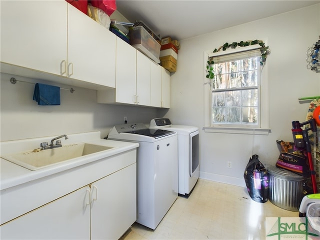 clothes washing area with washing machine and dryer, cabinets, and sink