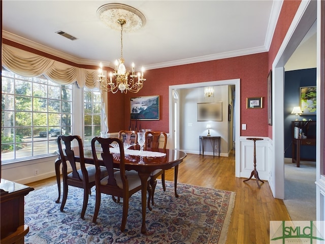 dining room with a chandelier, ornamental molding, and hardwood / wood-style floors