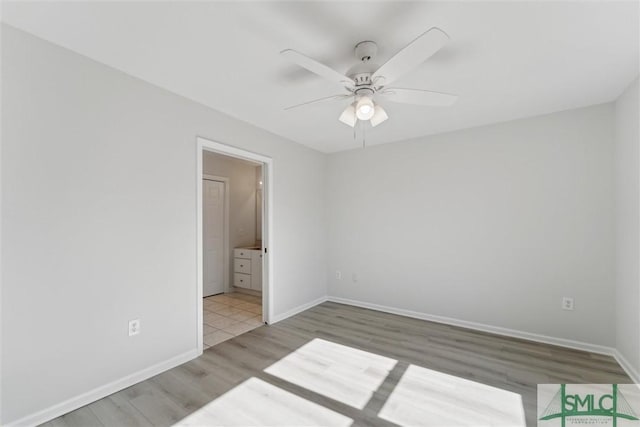 unfurnished bedroom featuring hardwood / wood-style floors, connected bathroom, and ceiling fan