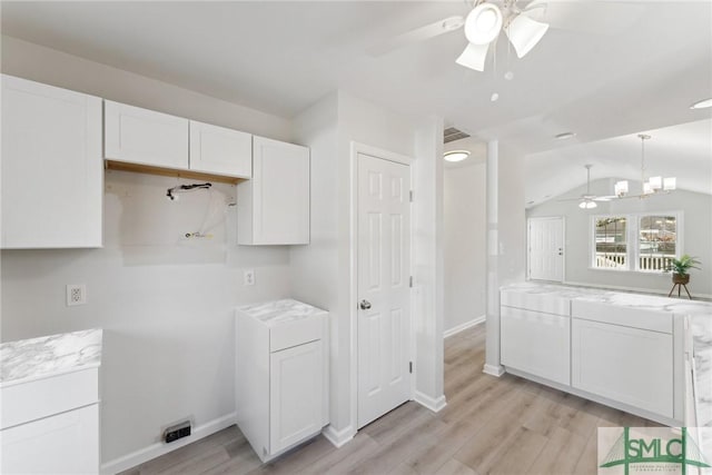 kitchen with ceiling fan with notable chandelier, light hardwood / wood-style floors, white cabinetry, and vaulted ceiling