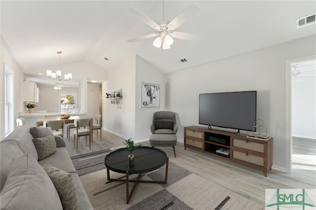 living room featuring vaulted ceiling, ceiling fan with notable chandelier, and light hardwood / wood-style flooring