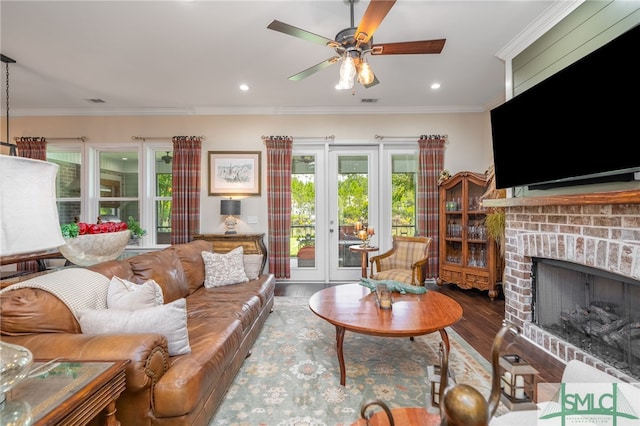 living room featuring a brick fireplace, hardwood / wood-style flooring, ornamental molding, and ceiling fan