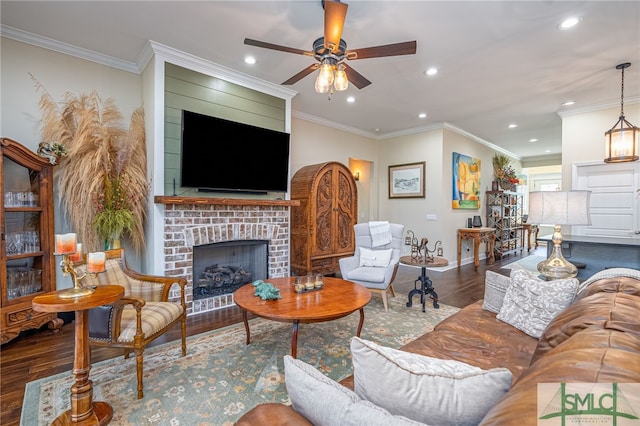 living room with ceiling fan, dark hardwood / wood-style floors, ornamental molding, and a brick fireplace