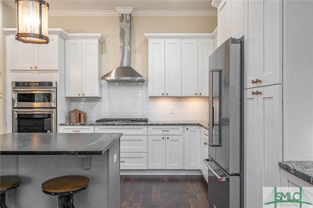 kitchen with backsplash, white cabinetry, appliances with stainless steel finishes, and wall chimney exhaust hood